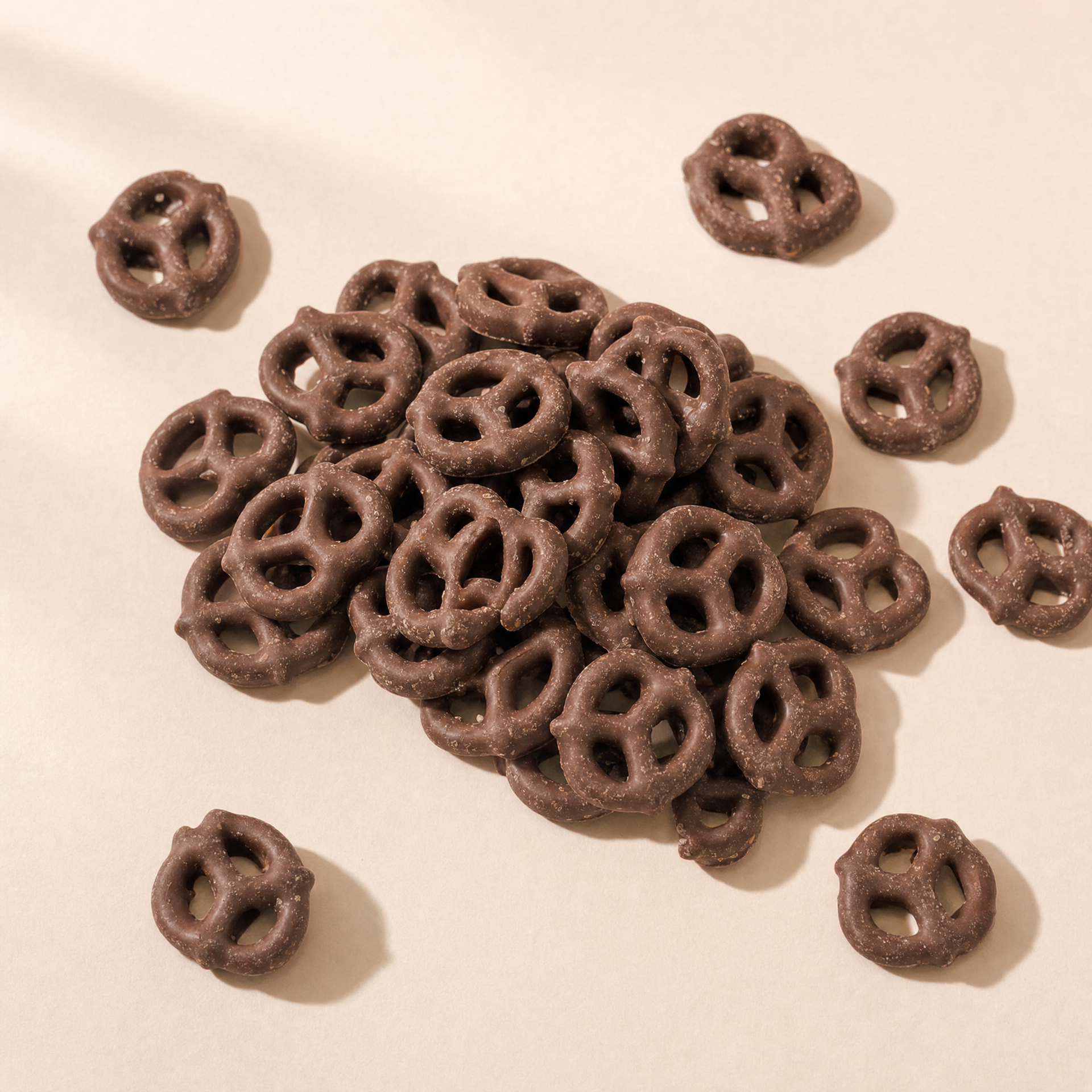 Pretzels crujientes cubiertos con chocolate con leche servidos sobre fondo claro