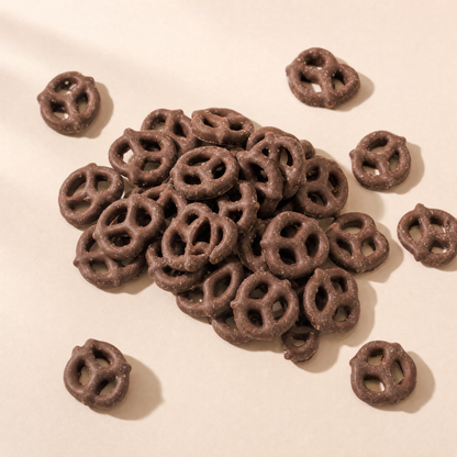 Pretzels crujientes cubiertos con chocolate con leche servidos sobre fondo claro
